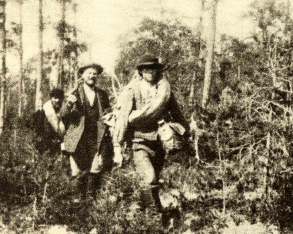 Kuvassa Vienan Karjalassa kävelemässä kuuluisat Kareliaanit kuhmolaisen oppaan, Renne Haverisen perässä Louis Sparre, ja Emil-Wikström.